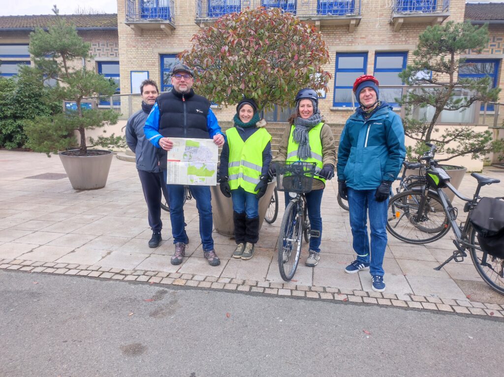 5 cyclistes devant la mairie des Clayes-Sous-Bois avec le plan de la ville